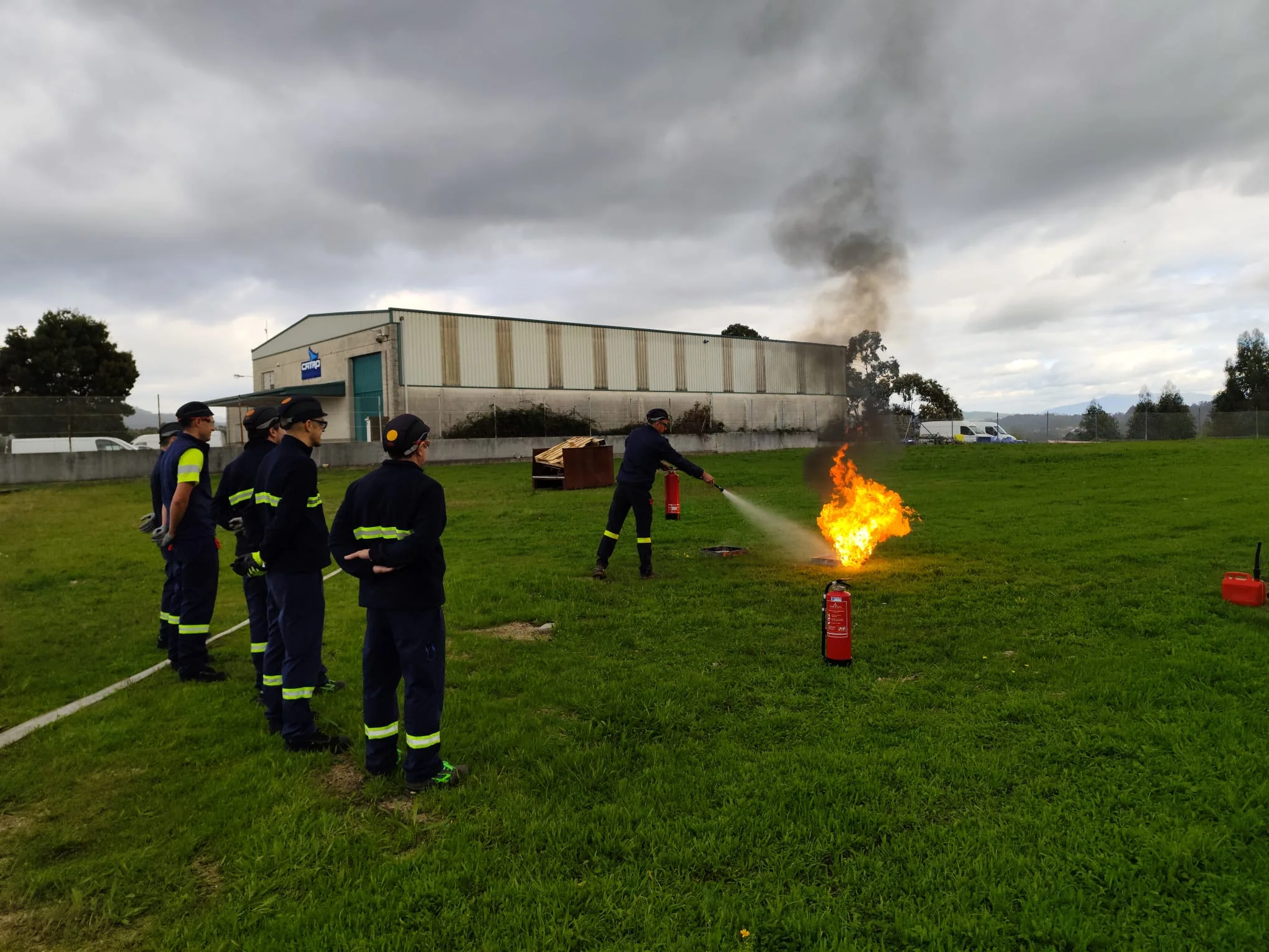 Práctica real de extinción de incendios con extintores realizada por un equipo en un entorno industrial